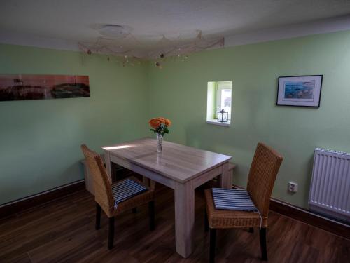 a dining room table with two chairs and a vase with flowers at Ferienwohnung Wieck Greifswald in Wieck