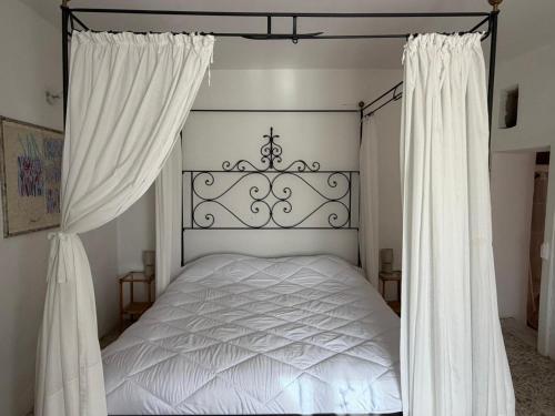 a bedroom with a white bed with white curtains at Luce su Civita in Lubriano