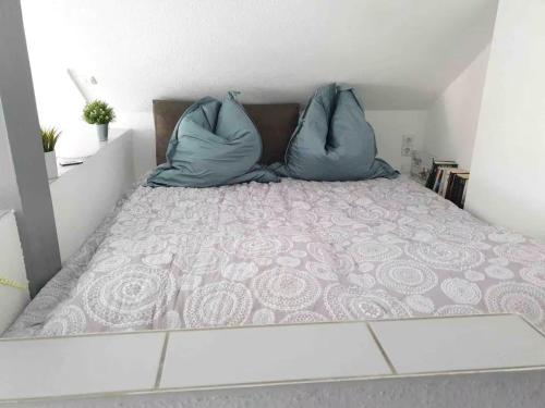 a bed with two blue pillows on top of it at Loft mit Kaminofen - Karlsdorf in Karlsdorf-Neuthard