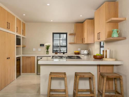 a kitchen with wooden cabinets and a counter with stools at Arc Guest House in Simonʼs Town
