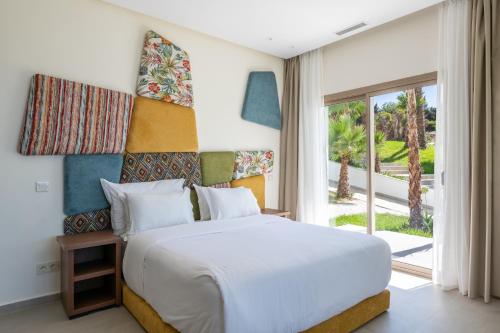 a bedroom with a white bed and a large window at Le Tanger Résidence Hôtelière in Tangier