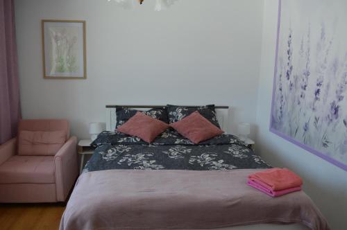 a bedroom with a bed and a pink chair at Mojone Izby in Maruszyna