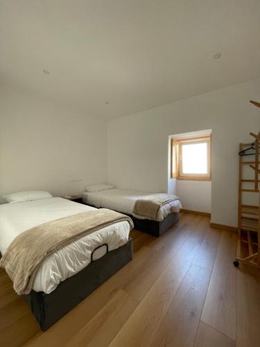 two beds in a room with a window at Casa Catalão in Montelavar