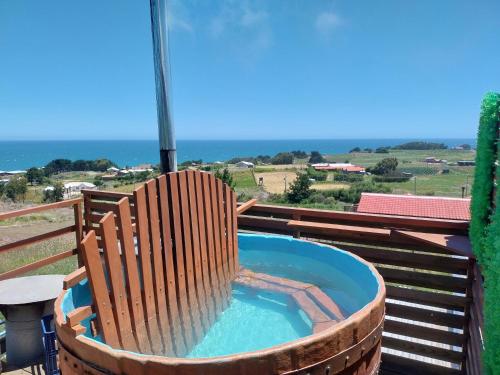 a wooden chair sitting in a hot tub on a balcony at Cabañas Bellavista del mar in De Cauquenes