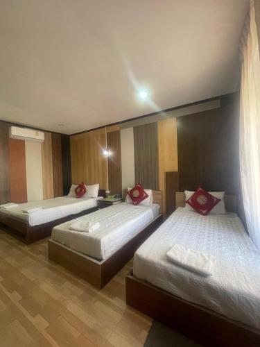 a room with three beds with red pillows on them at Vientiane Star Hotel in Vientiane