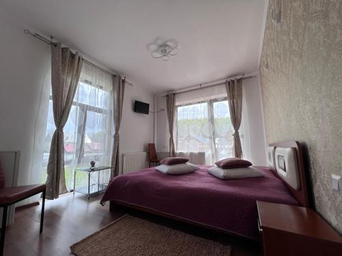 a bedroom with a purple bed and a window at Pensiunea Silvian in Cheia