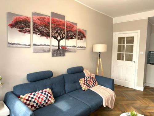a living room with a blue couch and a tree painting at Modern 3-Bed Flat Prime Falkirk Location in Falkirk