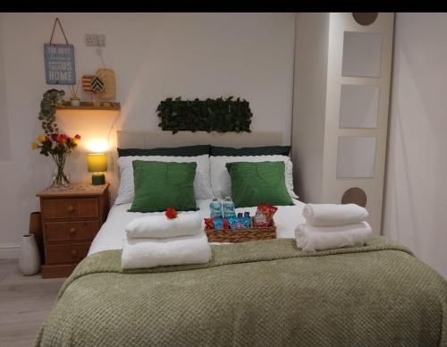 a bedroom with a large bed with green and white pillows at Cosy studio flat with free wifi and free parking in Killingbeck