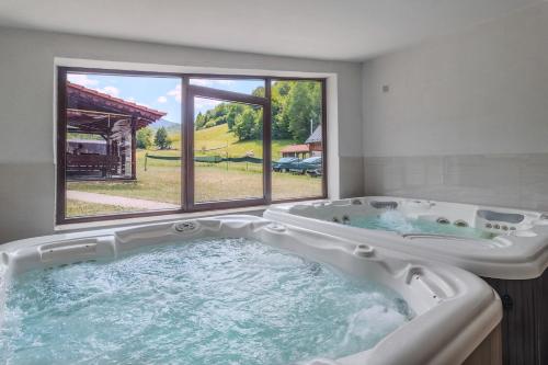 a large bath tub in a room with a window at Pensiunea Popasul Ursilor Medve Barlang Peștera Urșilor in Chişcău
