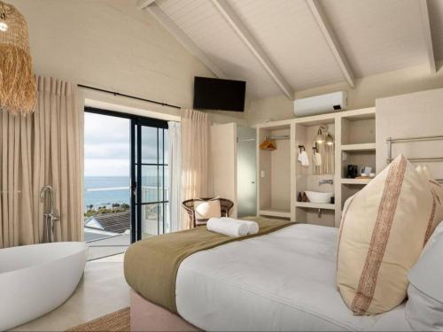 a bedroom with a tub and a bed and a bathroom at Arc Guest House in Simonʼs Town