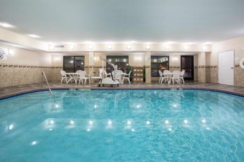 a large pool in a hotel with chairs and tables at Holiday Inn Express & Suites Ft Collins by IHG in Fort Collins