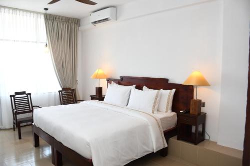 a bedroom with a large white bed and a window at Hotel Lanka Super Corals in Hikkaduwa