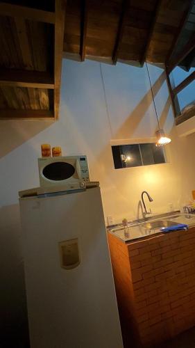 a small kitchen with a refrigerator and a sink at Casinha do Rosa in Imbituba