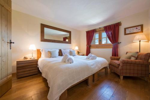 a bedroom with a large white bed and a chair at Chalet Dunmore in Verbier