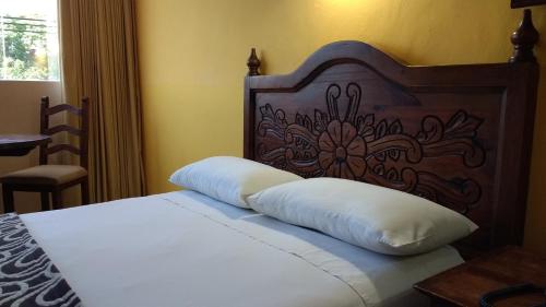 a bedroom with a bed with a wooden headboard at Suites Flamboyanes in Mérida