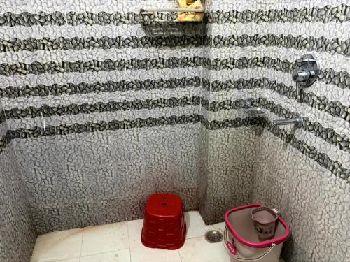 a bathroom with a shower with a red bucket on the floor at Good Vibes Retreat in Birbhaddar