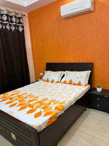 a bed in a bedroom with an orange wall at Good Vibes Retreat in Birbhaddar