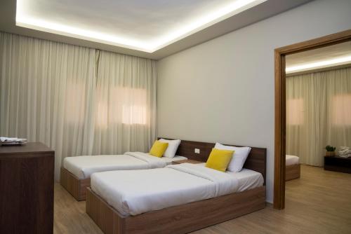 two beds in a hotel room with yellow pillows at Al Dora Boutique Hotel in Hurghada