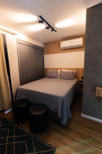 a bedroom with a bed and two stools in it at Flat exclusivo Studio Cuiabá 1207 in Cuiabá