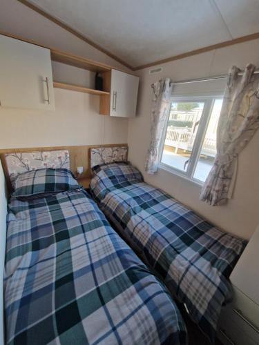 two beds in a small room with a window at Georgina Meadows in Skipsea