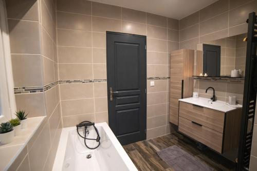 a bathroom with a black door and a sink at Chez Léon in Hasnon