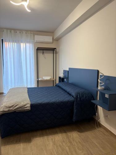 ein Schlafzimmer mit einem blauen Bett und einem Fenster in der Unterkunft Capizzi Rooms in Bronte