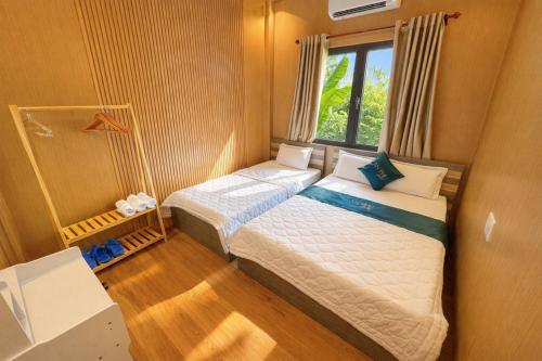 a small bedroom with two beds and a window at An Phú Villa in Cu Lao Thu