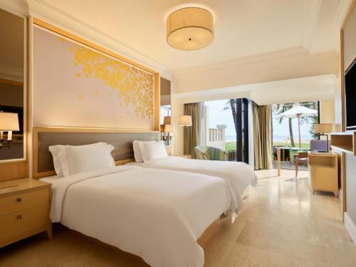 a bedroom with two white beds and a painting on the wall at Dusit Thani Laguna Phuket in Bang Tao Beach