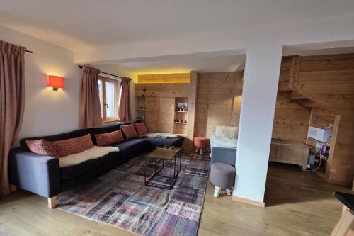 a living room with a black couch and a table at Roxes 6, duplex cosy et lumineux à proximité de Médran in Verbier