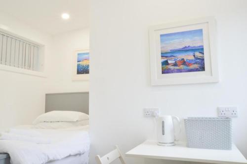 a white bedroom with a bed and a picture on the wall at Viewpoint Pods in Dunollie
