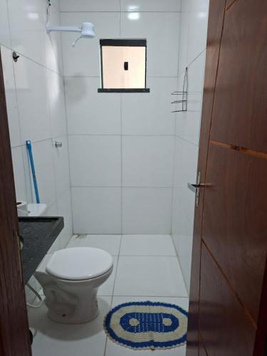 a white bathroom with a toilet and a window at Comfort right on the sand! in Paracuru