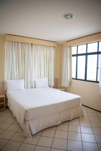a large white bed in a room with windows at Litorânea Praia Hotel in São Luís