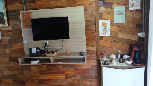 a television on a wall with a wooden wall at Casa de campo rústica 21km vila germânica Bnu in Blumenau