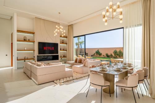 a living room with a table and chairs and a couch at Villa Atlas - Luxe - 4 Suites Modernes - Fitness - Piscine Chauffée - Terrain de Padel - Vue Montagne in Marrakesh
