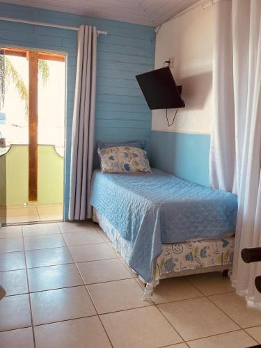 a bedroom with a bed and a flat screen tv at Vista Mar Praia da Lagoinha - Residencial Pé na Areia in Bombinhas