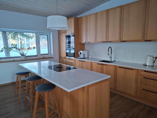 a kitchen with wooden cabinets and a island with bar stools at Puhkemaja Pühajärvel in Otepää