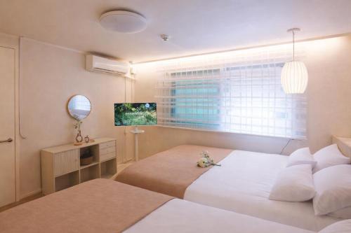 a bedroom with two beds and a window at Hongdae#Hongik Univ Station 9 min Walk#Airport Railroad Access#Free Parking#Free Netflix#Free WiFi#Luggage Storage#Washer and Dryer in Seoul