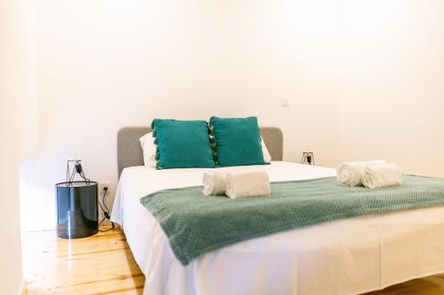 a bed with two green pillows on top of it at Magnificent Cais de Gaia Duplex in Vila Nova de Gaia