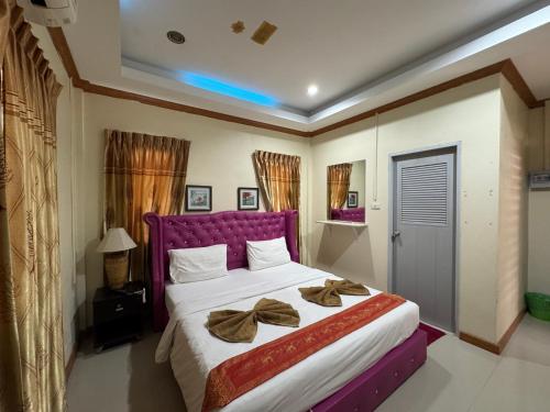 a bedroom with a large bed with a purple headboard at Ruen Thong Resort in Phang-nga