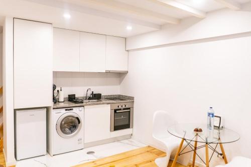 a kitchen with white cabinets and a washer and dryer at Magnificent Cais de Gaia Duplex in Vila Nova de Gaia