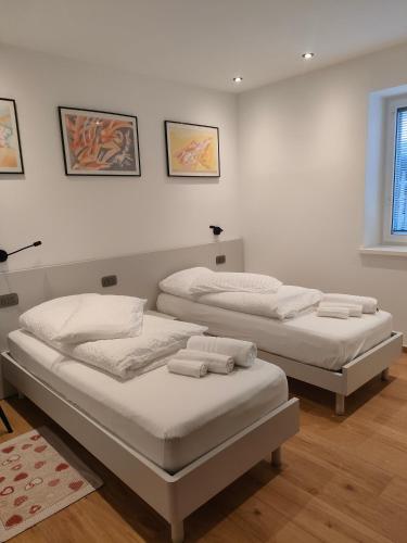 two beds in a room with white walls at appartamento PANORAMA in Pozza di Fassa