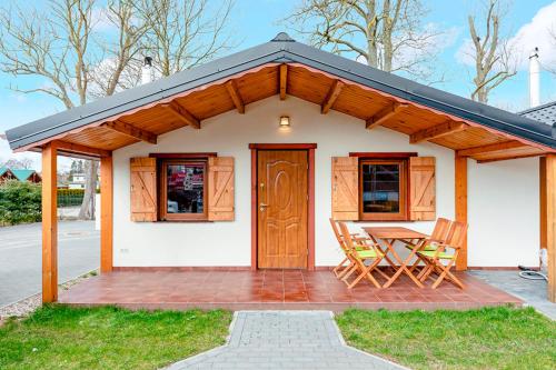 a small white house with a table and chairs at Ferienhaus Ustronie I Nr 1 in Ustronie Morskie