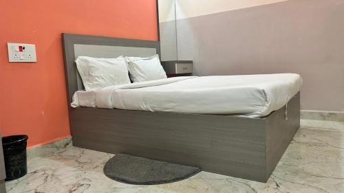 a bed with white sheets and pillows in a room at Hotel Monsoon in Warangal