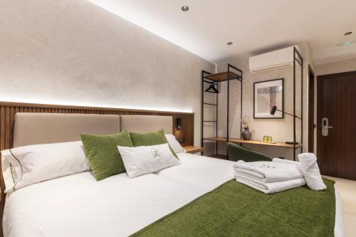 a bedroom with a large white bed with green pillows at Amaranta Hotel Boutique in Ronda