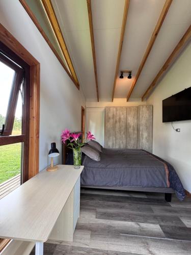 a bedroom with a bed and a desk and a window at Casa en el bosque-tinaja in Puerto Octay