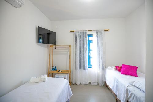 a white room with two beds and a window at QUINTAL DO SON CHALÉS in Ubatuba