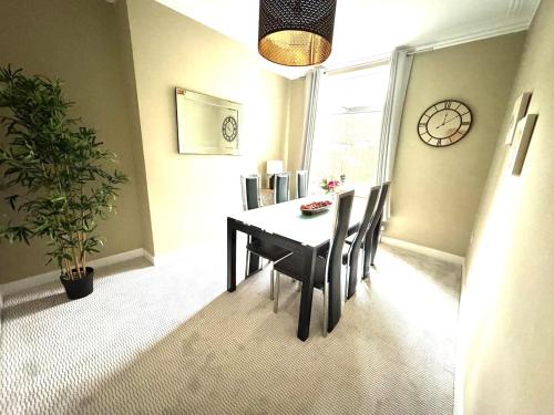 a dining room with a table and chairs and a clock at Stylish home from home in Nether Edge