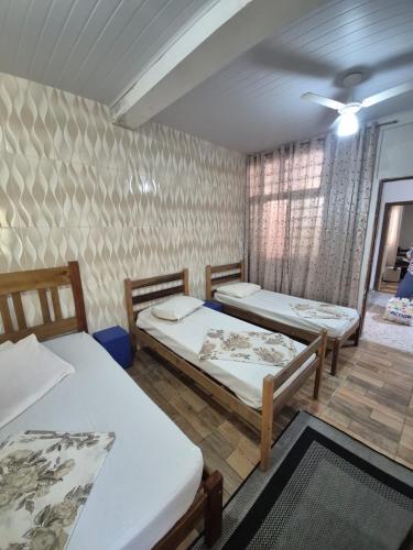 a room with three beds in a room at Pousada A CASA DE IRENE in Aparecida