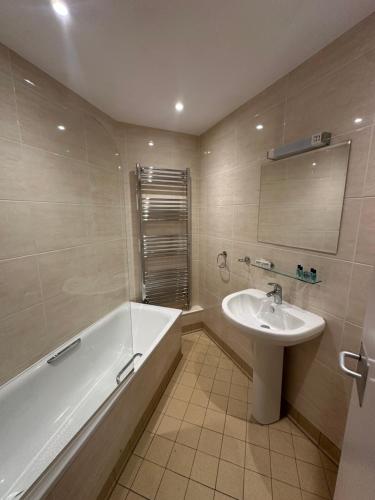 a bathroom with a bath tub and a sink at Cavendish Hotel in High Wycombe