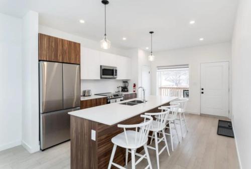 a kitchen with white walls and a large island with bar stools at Winnipeg Airport & Polo Park Suites in Winnipeg
